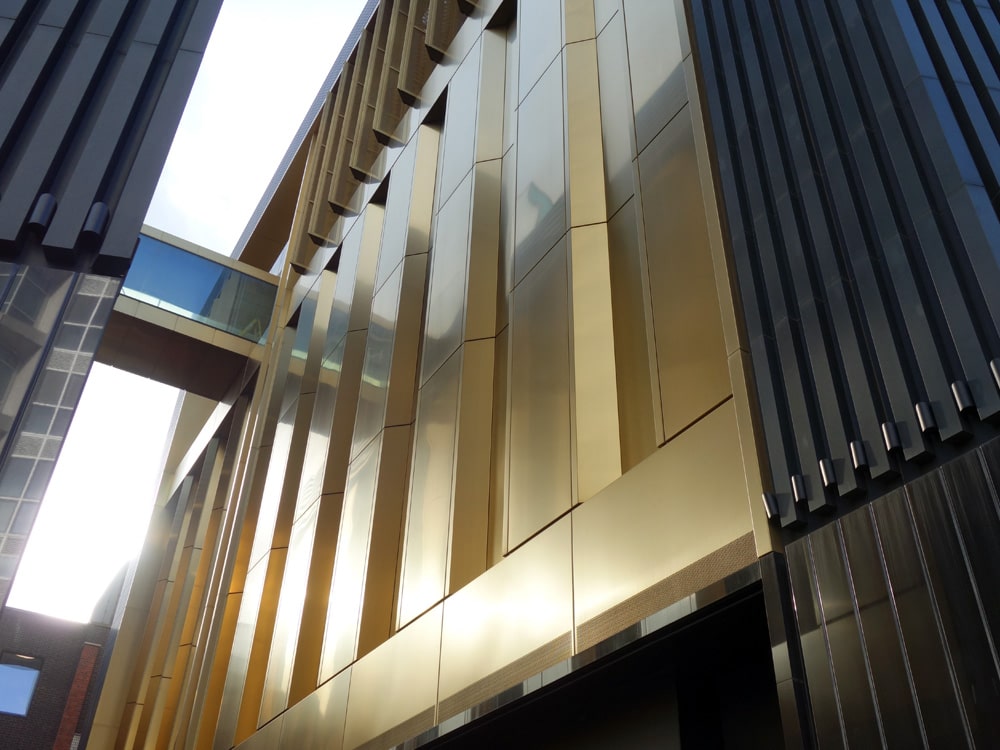 Gevelbekleding in Hairline RVS met gouden PVD Gold-TiN coating, dynamisch aanzicht van de gevel