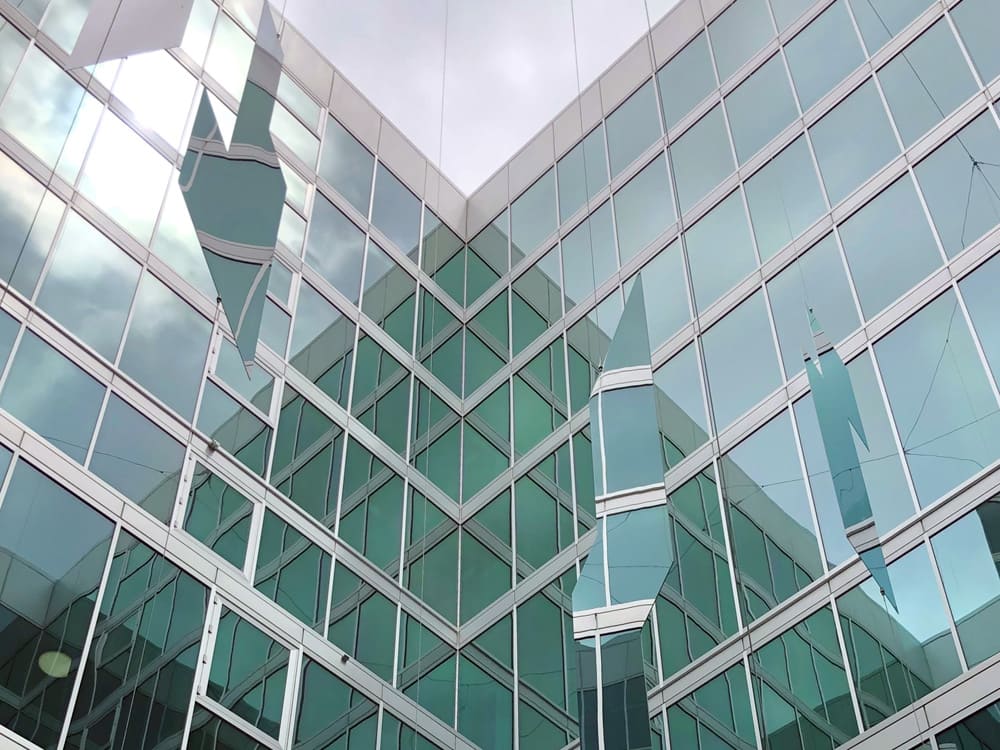 Marine Mirror 9 RVS spiegelpanelen als hangende kunstinstallatie in een glazen atrium
