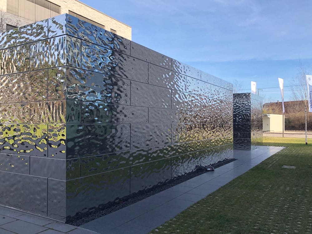 Gevelbekleding in Swell/Water Ripple RVS, diagonaal aanzicht met sterke reflectie van lucht en omgeving